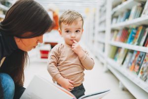 Cute baby boy toddler child in bookstore with mother